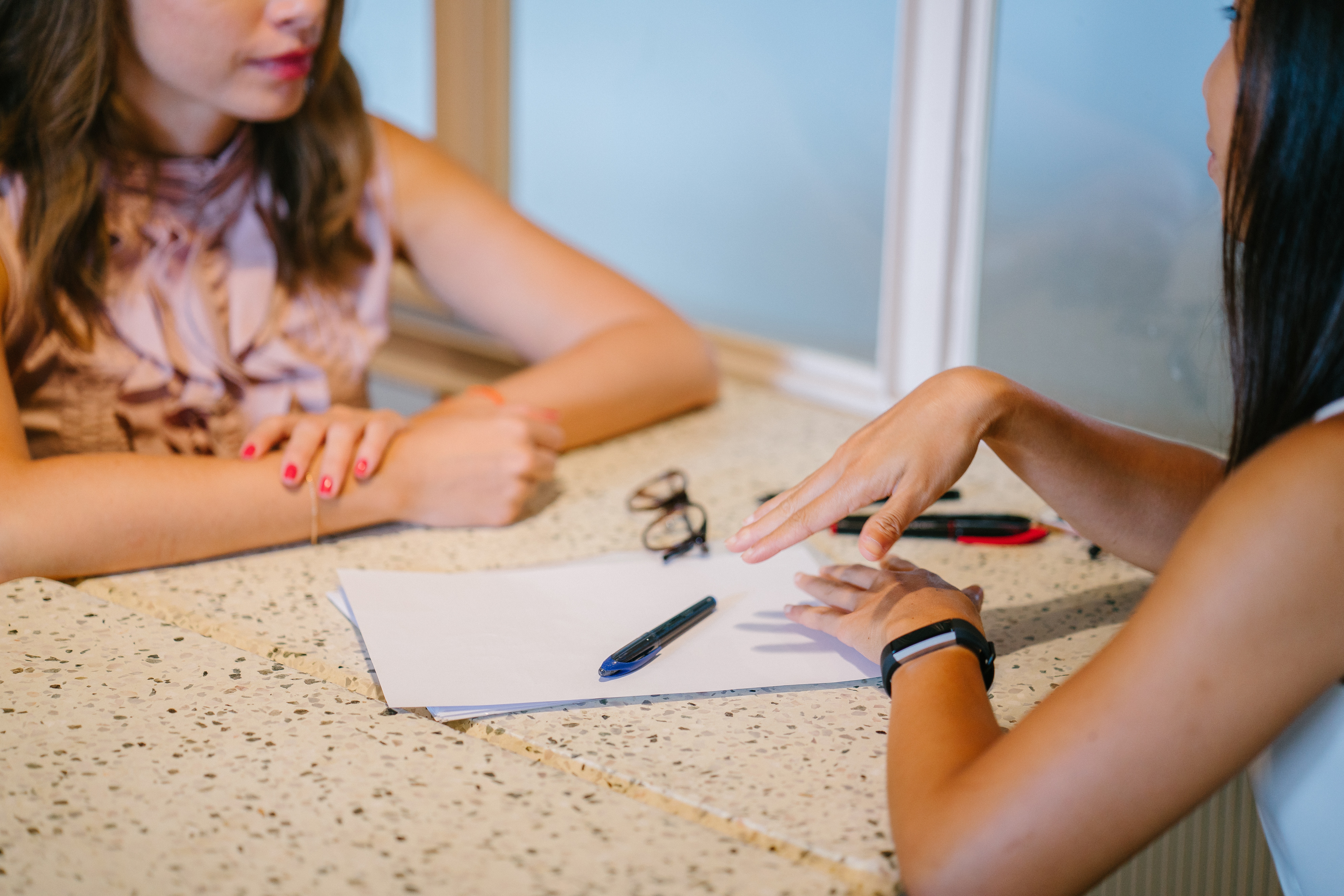 Two people seated across from each other at a table reviewing paperwork during a conversation